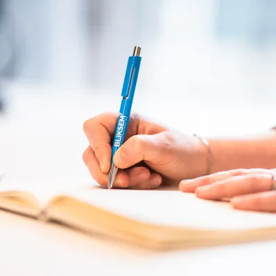 Persoon maakt notities met balpen van Bliksem Schrijfbureau