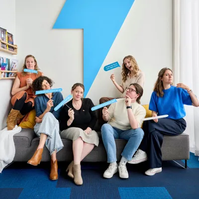 Teamfoto van Bliksem op de zetel. Elke copywriter houdt een bordje met oneliner in de lucht.