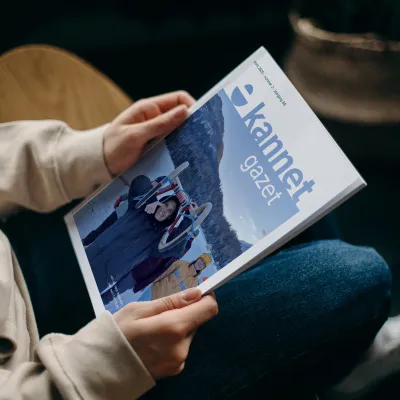 Persoon zit neer en heeft Kannet magazine in de hand