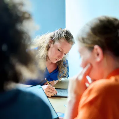 Marlies neemt notities tijdens het teamoverleg met Bliksem Schrijfbureau