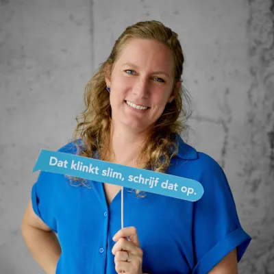 Copywriter Marlies Decavel met blauwe tekstballon in de hand waarop staat "dat klinkt slim, schrijf dat op."