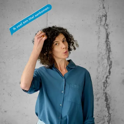 Copywriter Petra Broeders met blauwe tekstballon in de hand waarop staat "ik voel een titel aankomen."